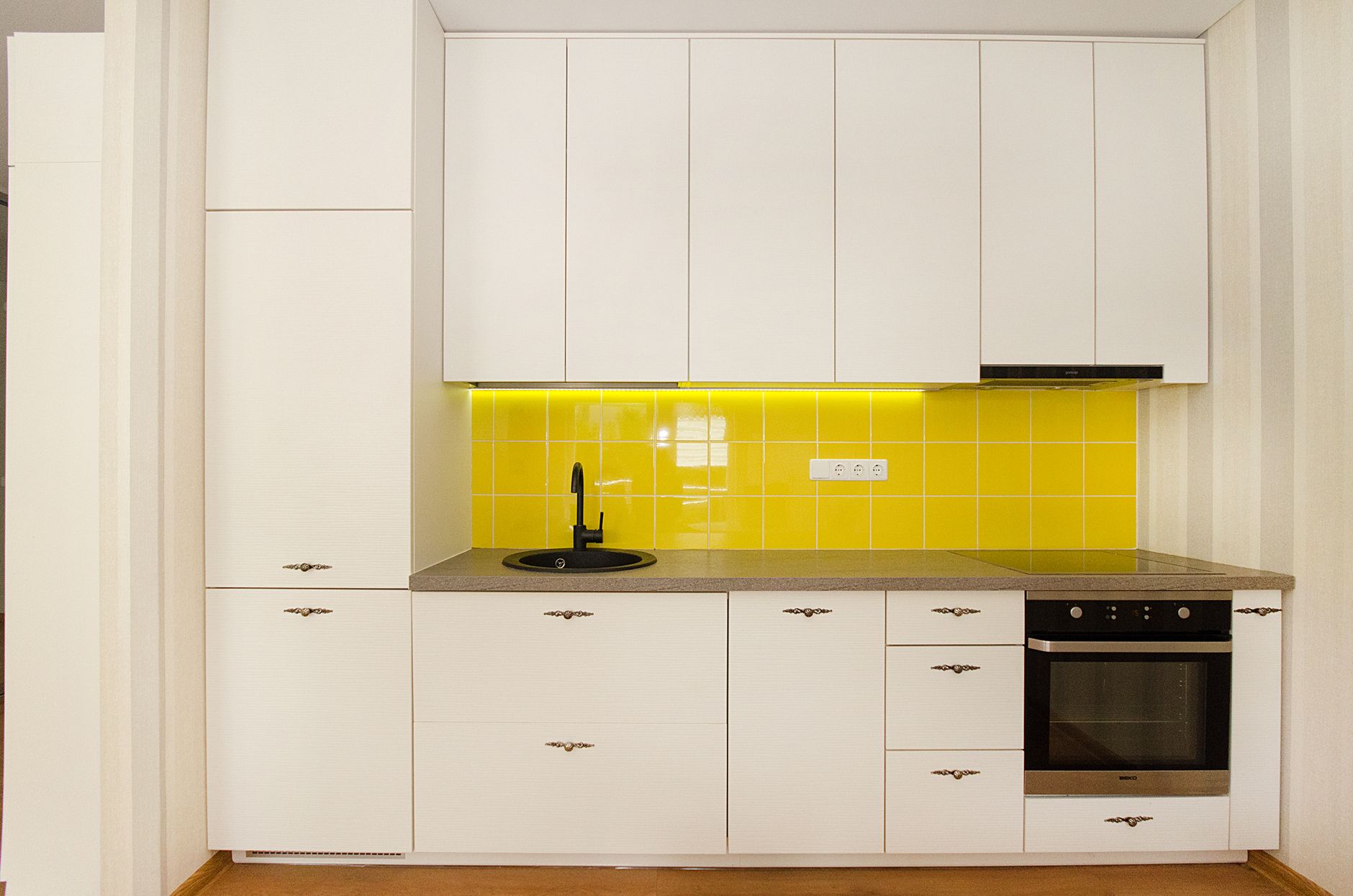 Stylish modern kitchen with white cabinets and a vibrant yellow tile backsplash in Austin, TX