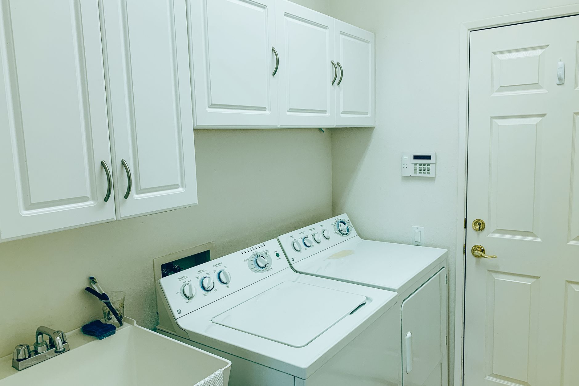 Well-organized laundry space with a washing machine, dryer, and white cabinets in Austin, TX